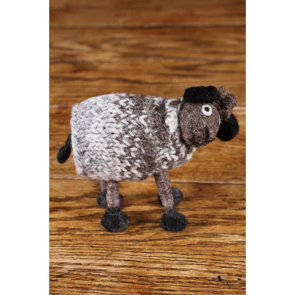 Felted wool Pachamama sheep figurine, gray and black with detailed features, on wooden surface.