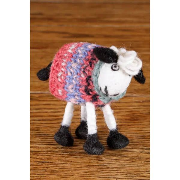Felted Pachamama-themed sheep plush toy with multicolored wool body, white face, and black details, placed on wooden surface.