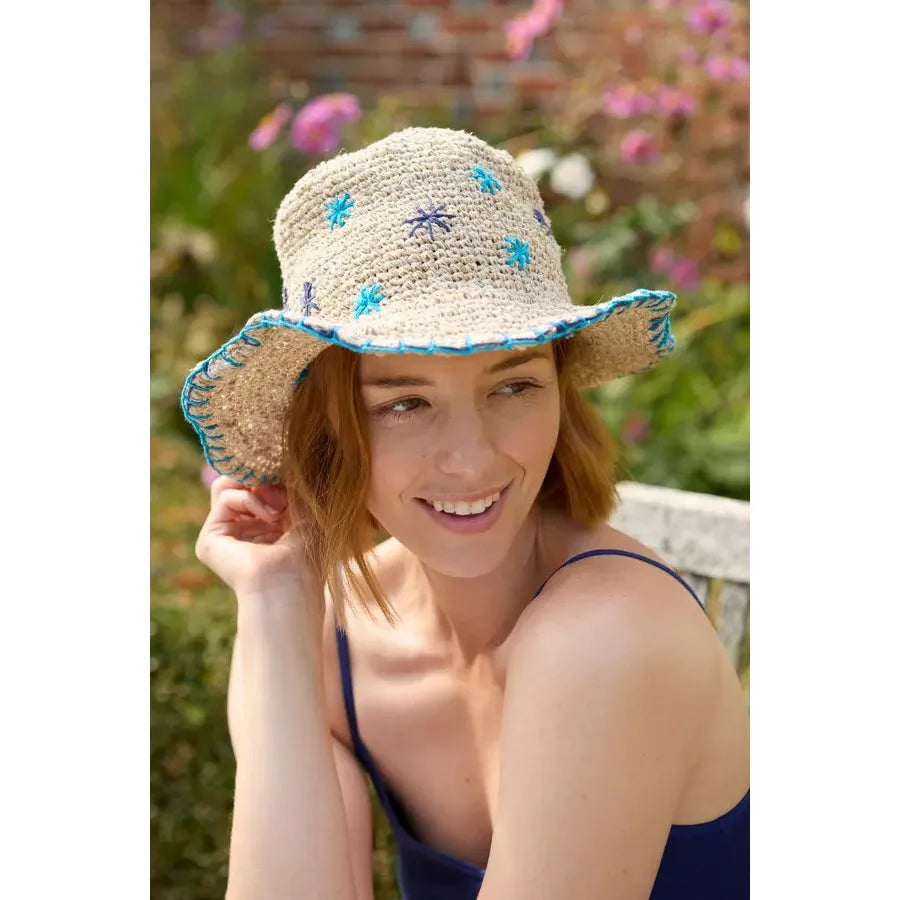 Pachamama Wildflower hemp and cotton sun hat in blue with embroidered floral details, brim, and adjustable fit.