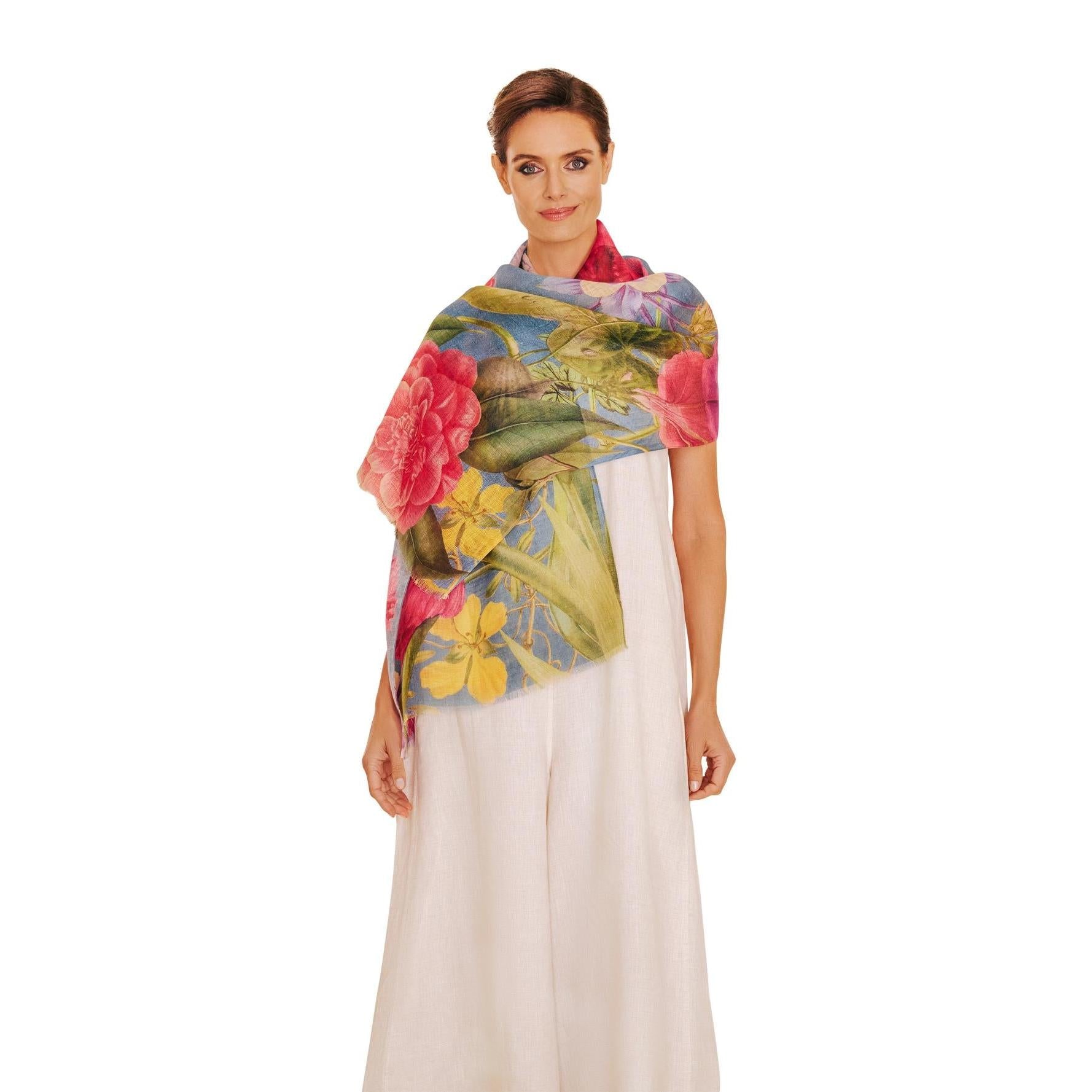 Powder floral study linen and cotton blend scarf in denim with colorful flower print, draped over a woman's shoulders.