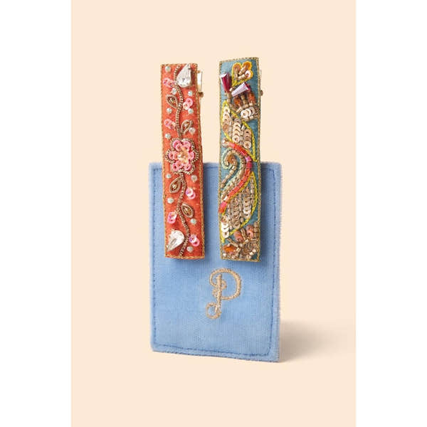 Powder narrow jeweled hair bar with orange floral and teal festival design, displayed on a blue velvet pouch.