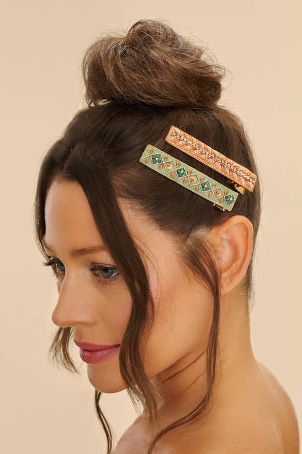 Powder ribbon and strike narrow jeweled bar hair clips in pastel colors, worn on side of brunette woman's updo hairstyle.
