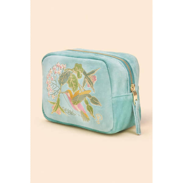 Powder velvet makeup bag featuring embroidered hummingbird and floral design, in soft blue with gold zipper detail.