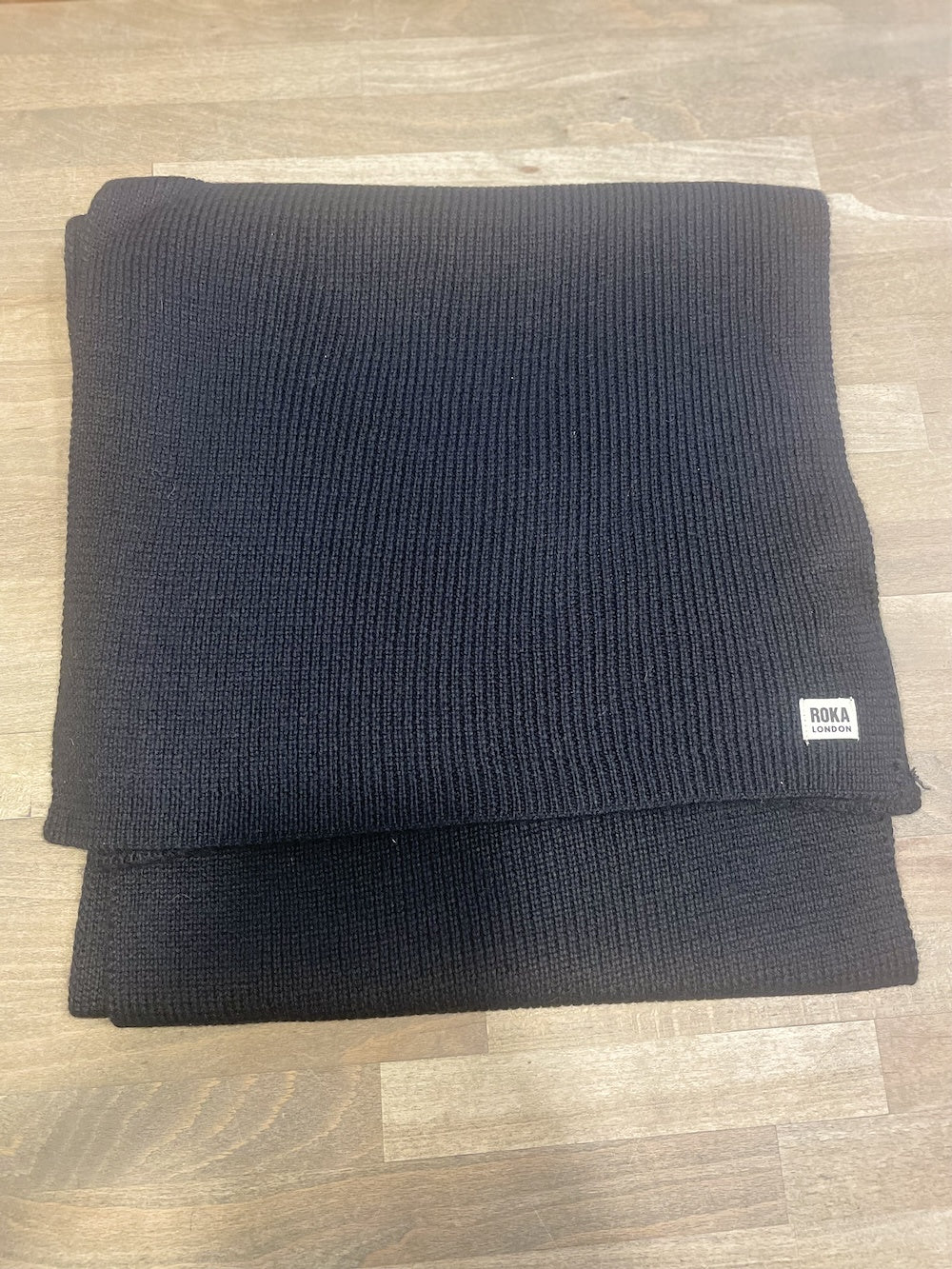 ROKA London Hyde Black Scarf, ribbed knit, stylish and warm, men's accessory, folded on wooden surface.