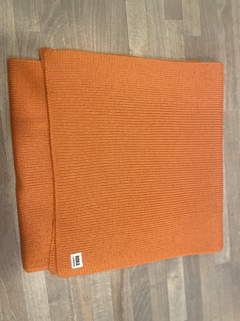 ROKA London Hyde Burnt Orange scarf, textured knit, stylish accessory, lightweight, fashionable, warm, versatile, orange color.