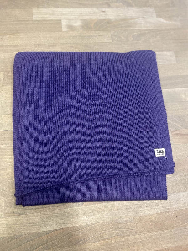 Royal purple ROKA London Hyde Peri scarf, ribbed knit fabric, folded neatly on wooden surface.