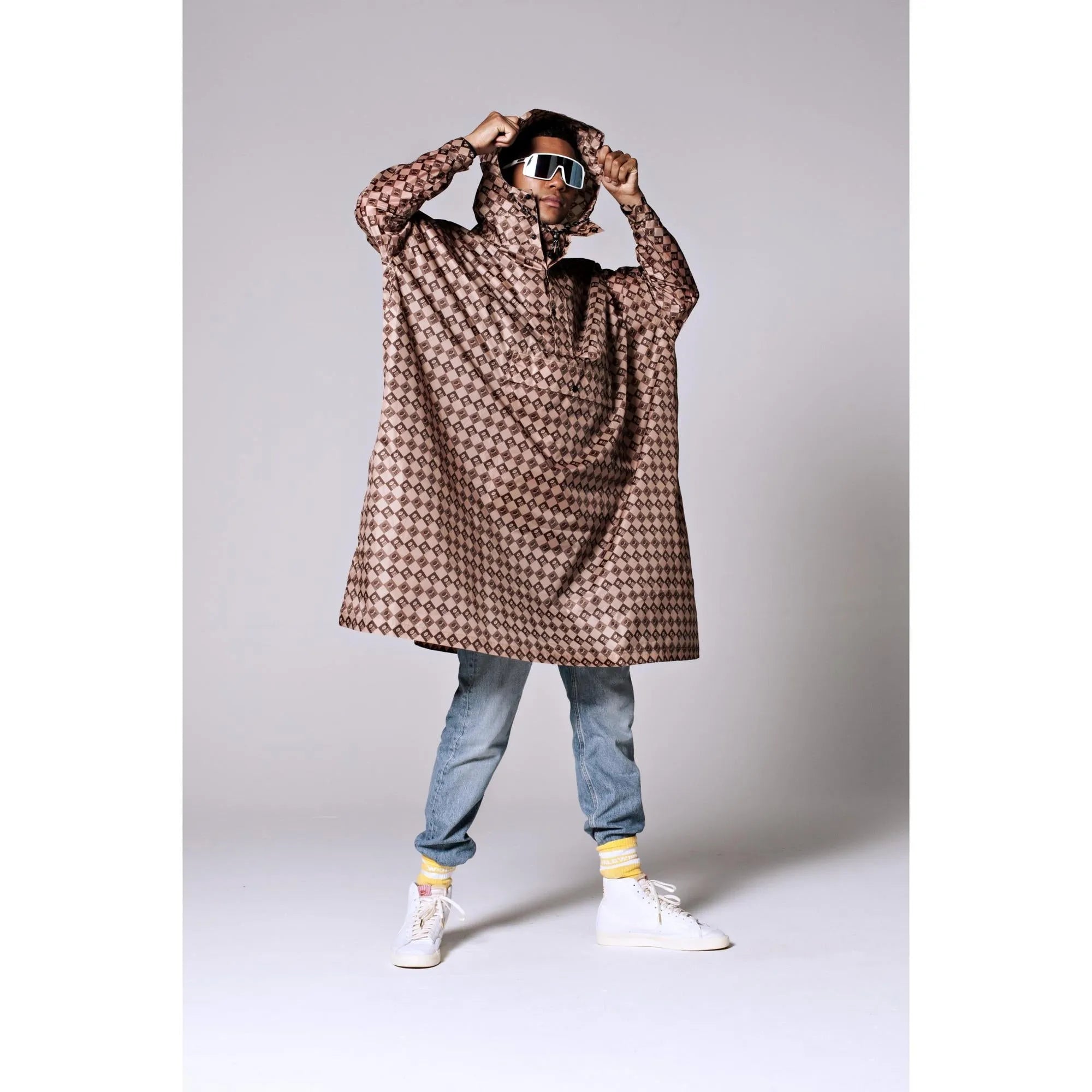 Rainkiss Damier rain poncho with geometric pattern, hood, and waterproof fabric, styled for fashion-forward protection.