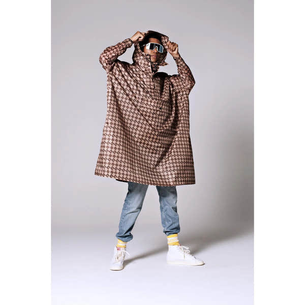 Rainkiss Damier rain poncho with geometric pattern, hood, and waterproof fabric, styled for fashion-forward protection.