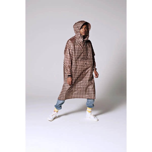 Rainkiss Damier rain poncho with hood, brown checkered pattern, oversized fit, paired with jeans and sneakers, designed for rainy weather.