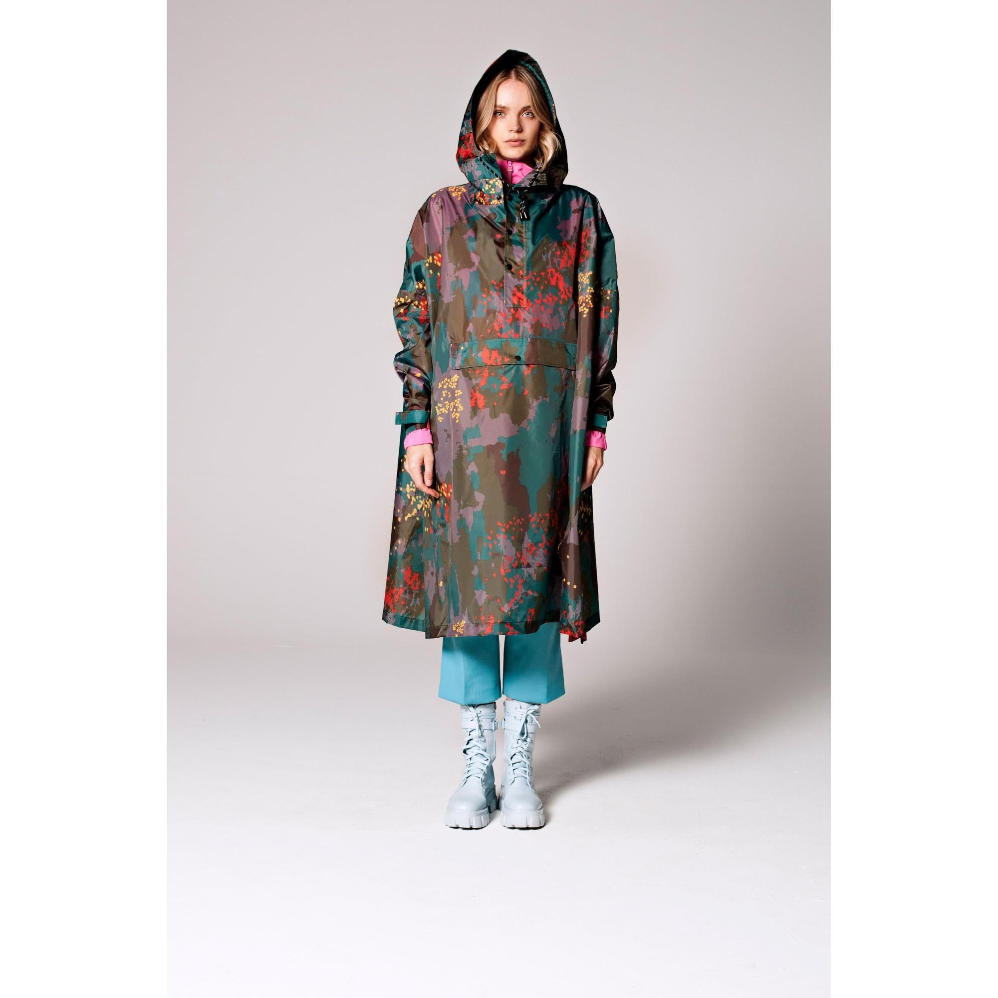 Rainkiss Digi Forest Camo rain poncho with hood, colorful camouflage print, long length, and white combat boots.
