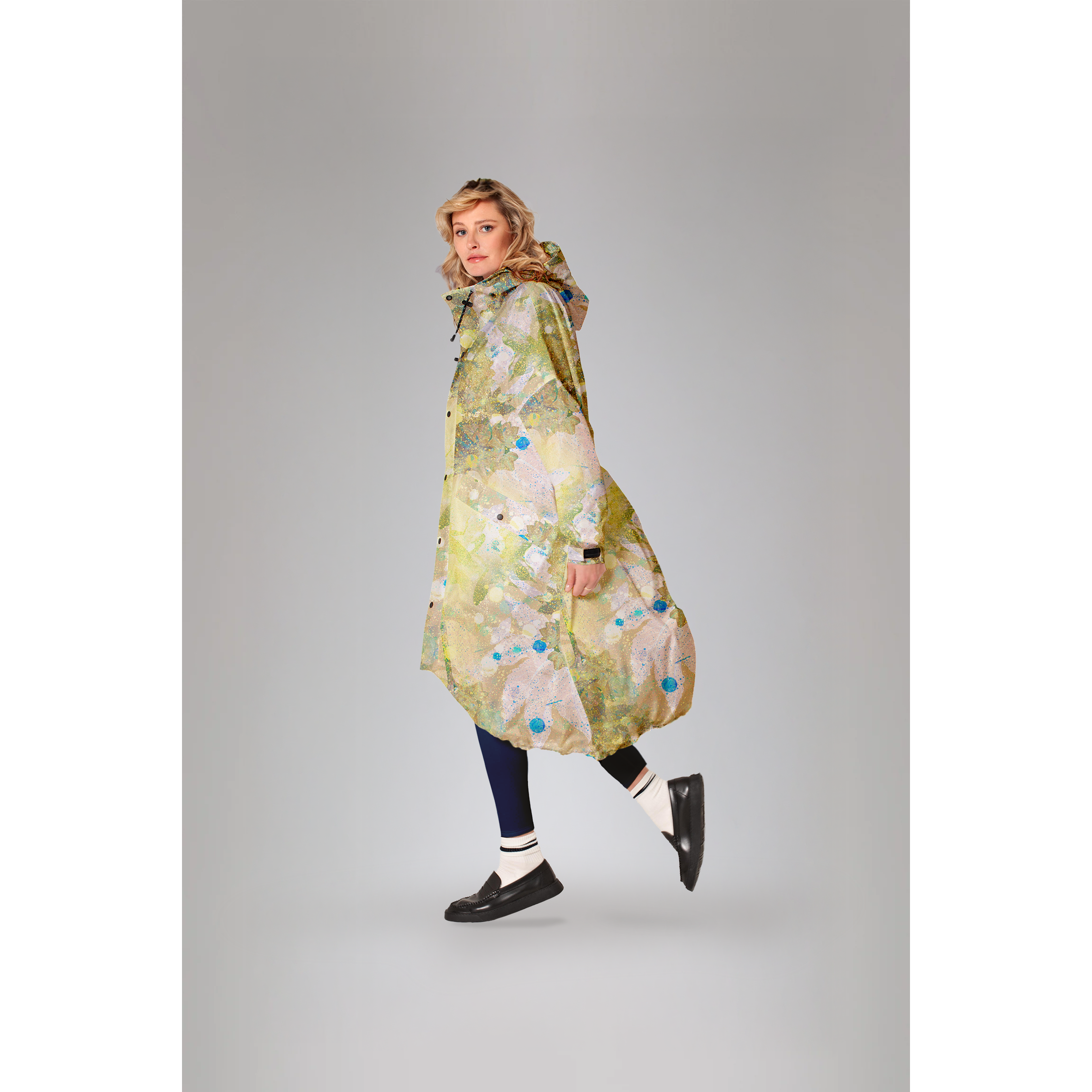 Rainkiss Flora green raincoat with botanical print; model wearing the coat in a three-quarter side view.