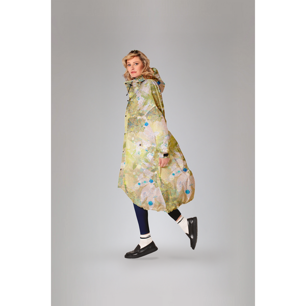 Rainkiss Flora green raincoat with botanical print; model wearing the coat in a three-quarter side view.