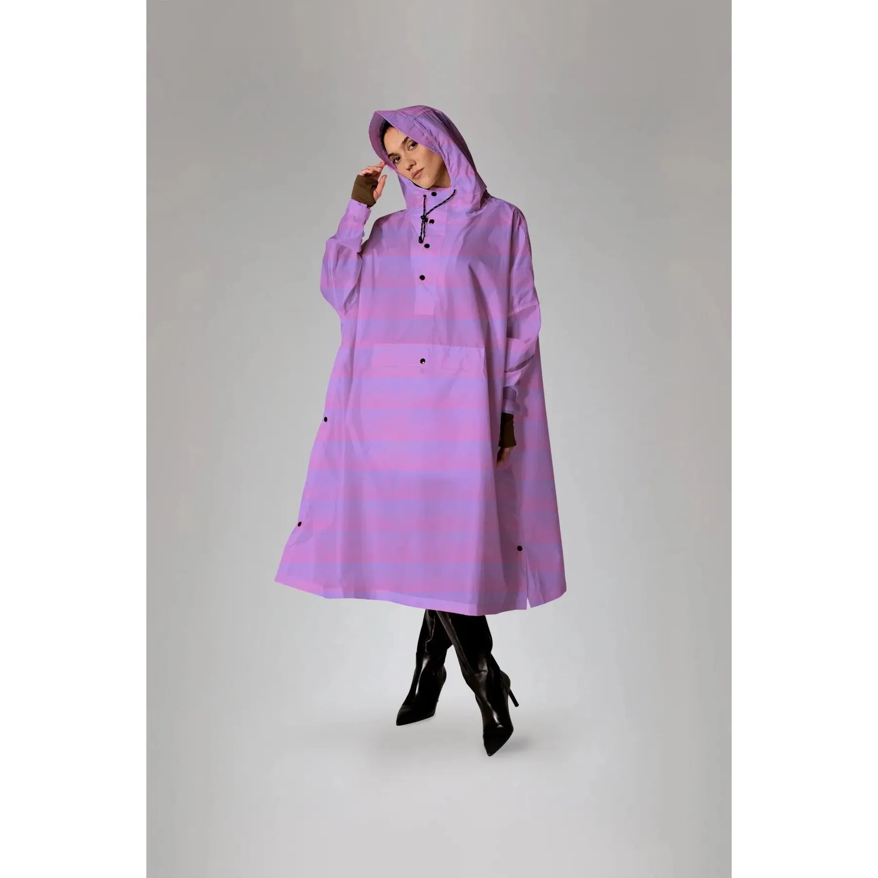 Rainkiss Seeing Stripes Purple Rain Poncho worn by a model, featuring a purple rain-patterned design with a hood and button closure.