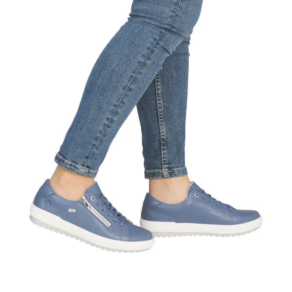 Blue leather lace-up shoes with a zip detail and white sole, worn with fitted jeans, showcasing a casual, stylish look.