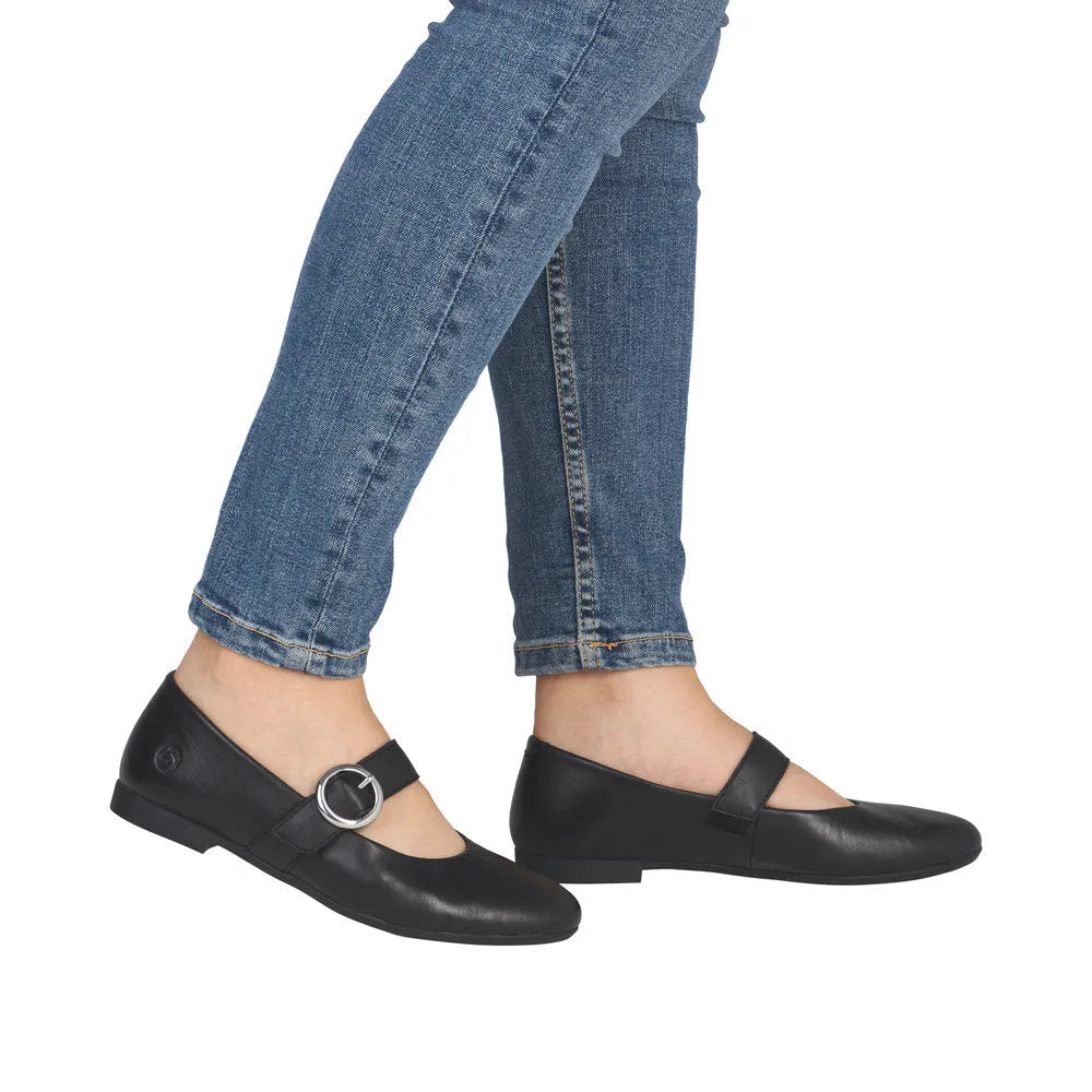 Black leather touch fastening shoes with a metallic buckle, paired with blue skinny jeans, showcasing a simple, elegant style.