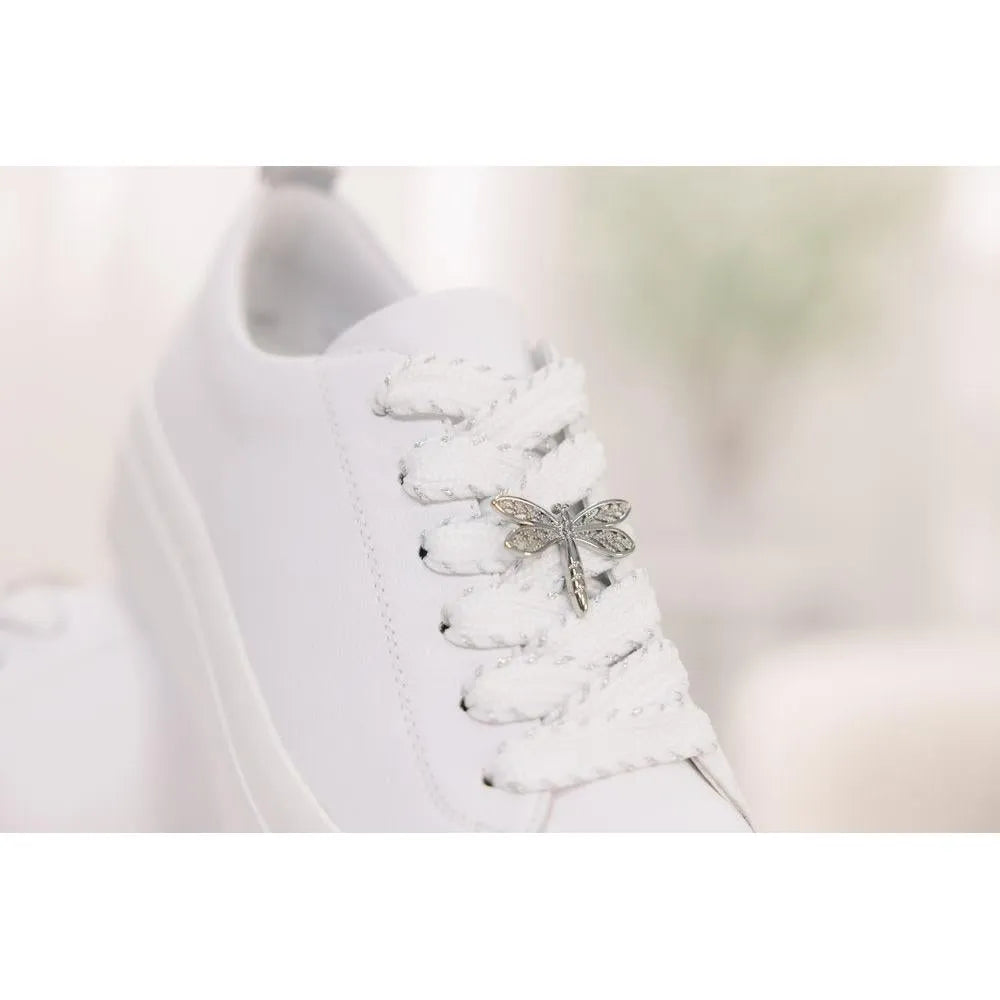 White leather lace-up shoe with a dragonfly charm on the laces, clean and minimalist style.