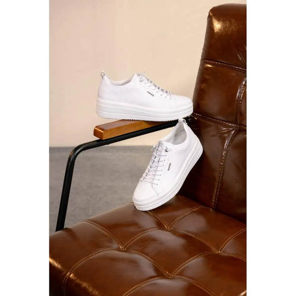 White leather lace-up shoes with a chunky sole, minimalist design, and subtle branding details.