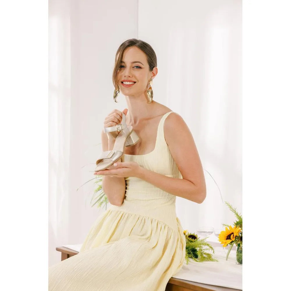 Women’s pale gold leather sandal with touch fastening, low heel, stylish design, and elegant appearance.