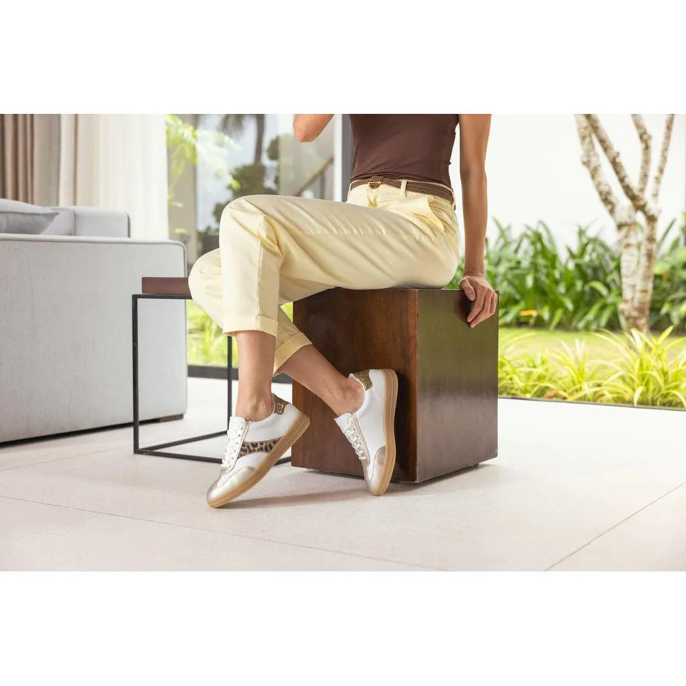 White and leopard lace-up trainers with beige accents, styled casually with light yellow pants in a bright setting.