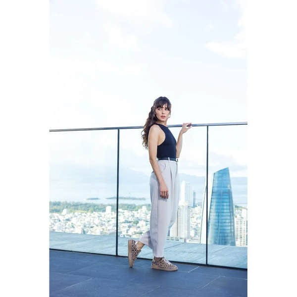 Woman standing on a balcony with a cityscape view wearing remonte leopard print trainers