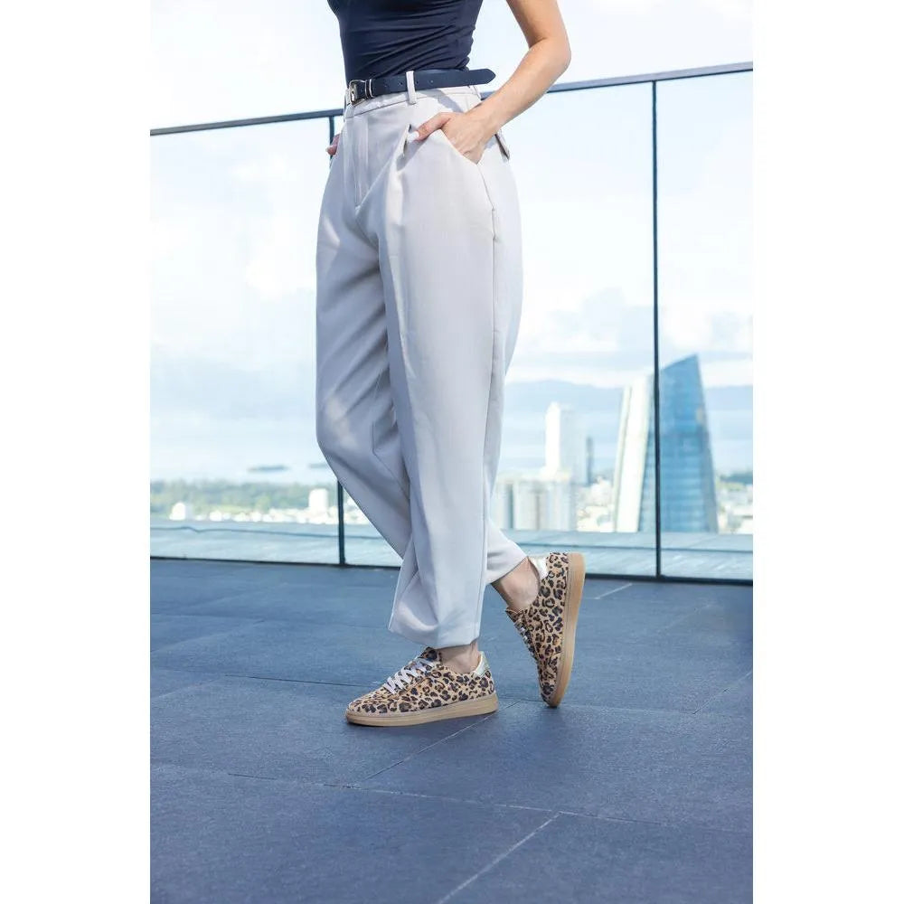 Person wearing white pants and leopard print shoes on a rooftop with cityscape background