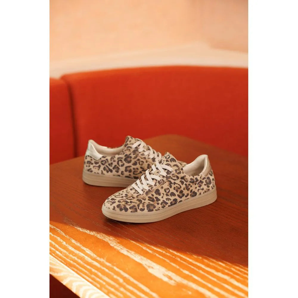Leopard print sneakers on a wooden surface with an orange background