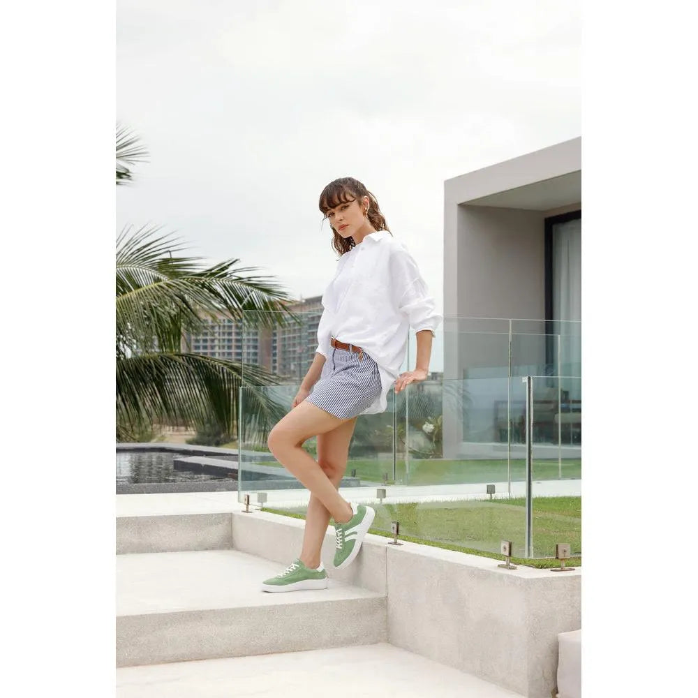 Women's wide green suede lace-up shoes with white soles, styled with casual summer outfit.