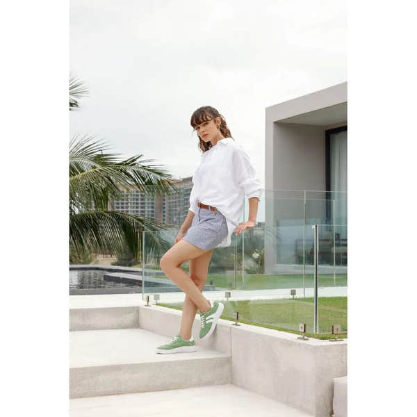 Women's wide green suede lace-up shoes with white soles, styled with casual summer outfit.
