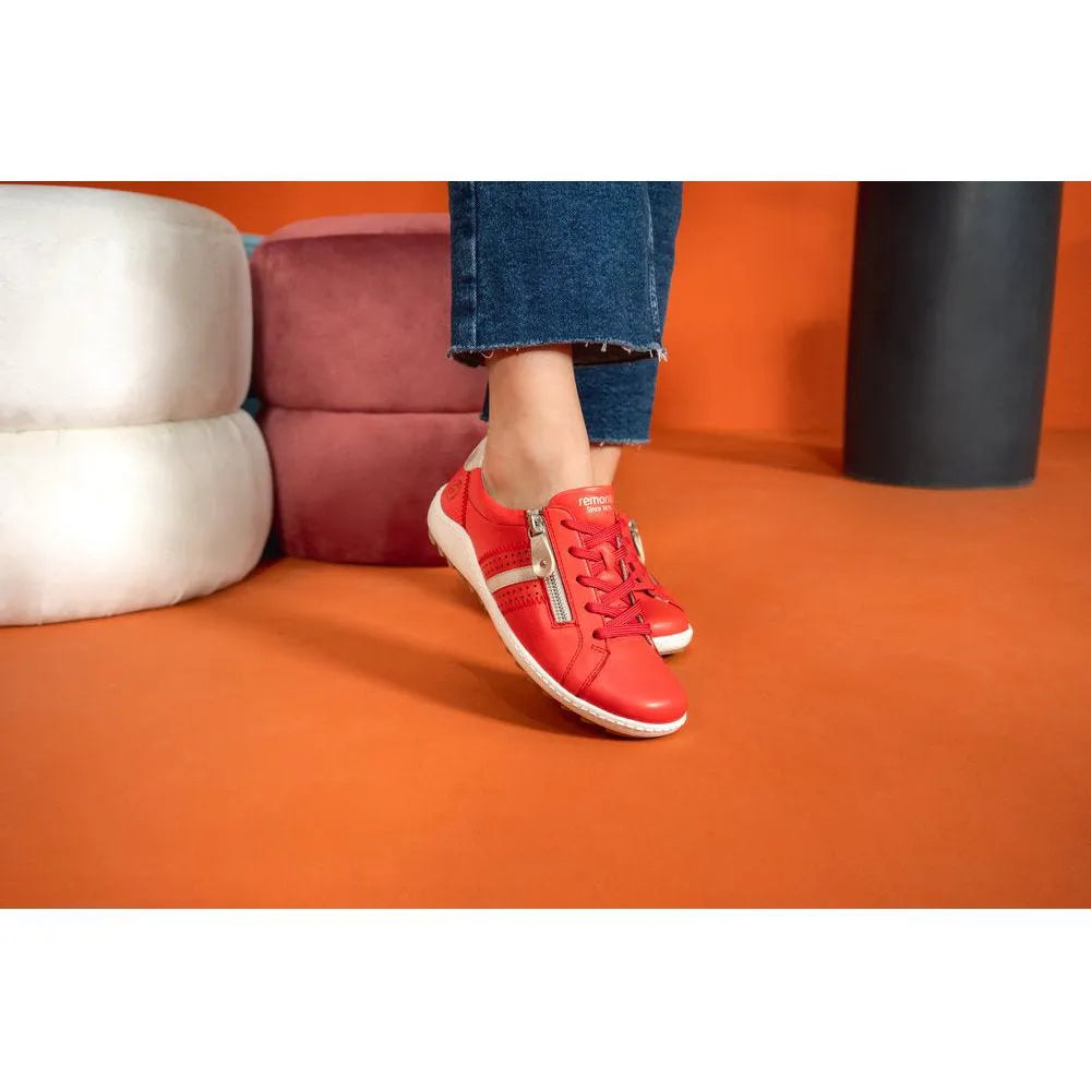 Red leather women's shoes with zip, laces, and white sole, styled casually with cropped jeans.