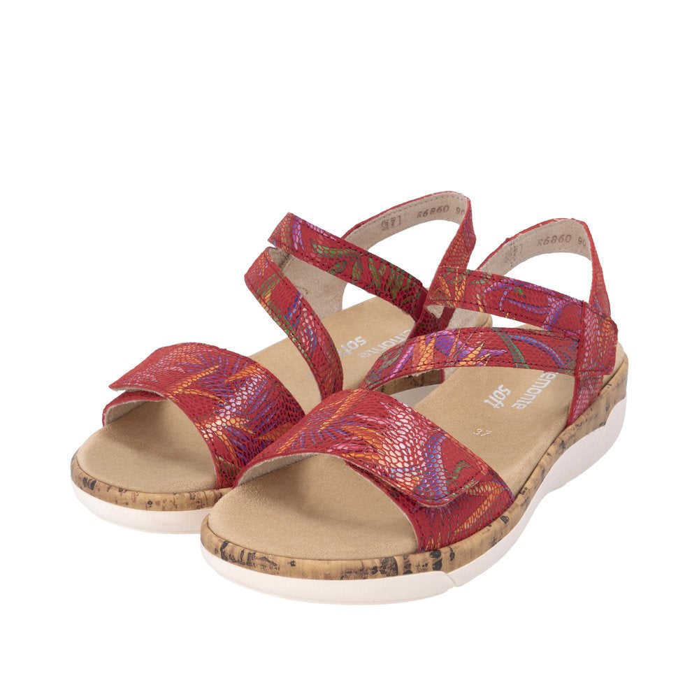 Red leather touch fastening ladies’ sandals with colorful patterned straps and cork and white sole.