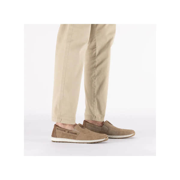 Beige slip-on deck shoes with perforated details and white rubber soles, worn with beige pants.