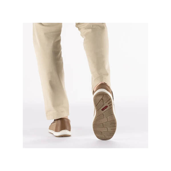Back view of beige slip-on deck shoes with brown accents, white soles, and textured rubber outsole on a person in beige pants.