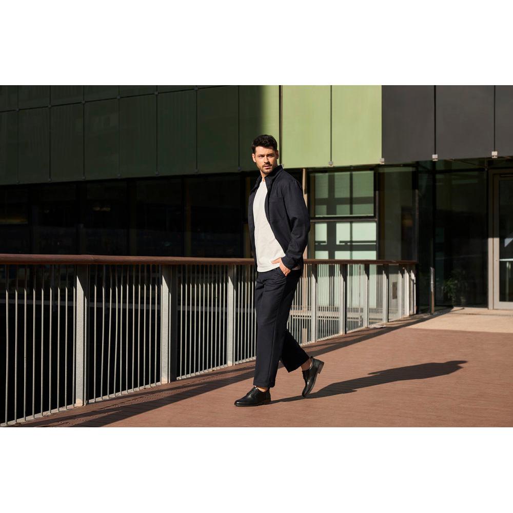 Rieker 10353-00 men's wide-fit black leather slip-on shoes in casual style worn by a man outdoors.