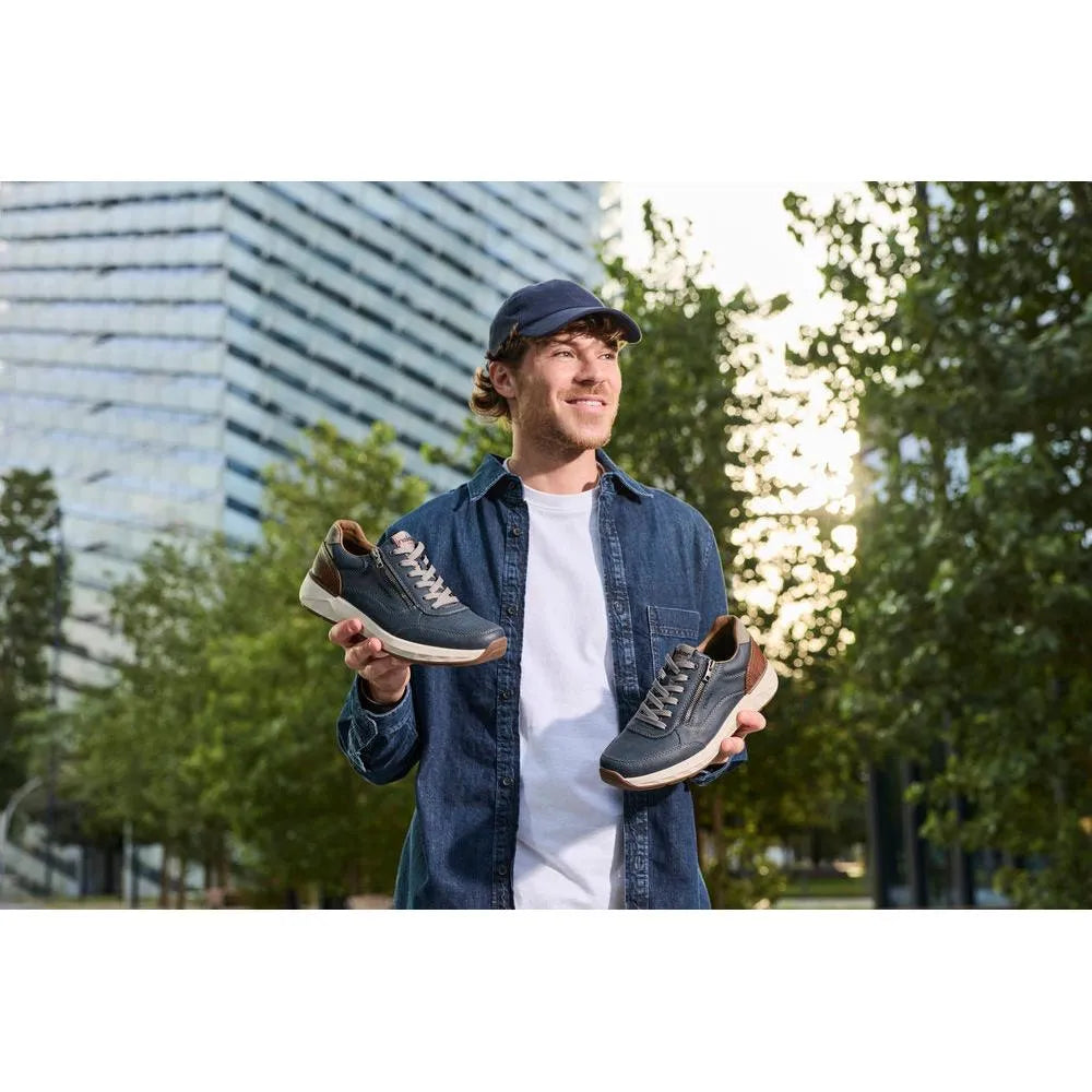 Man holding Rieker 11504-14 men's wide midnight zip and lace shoes outdoors, styled with denim shirt and cap.