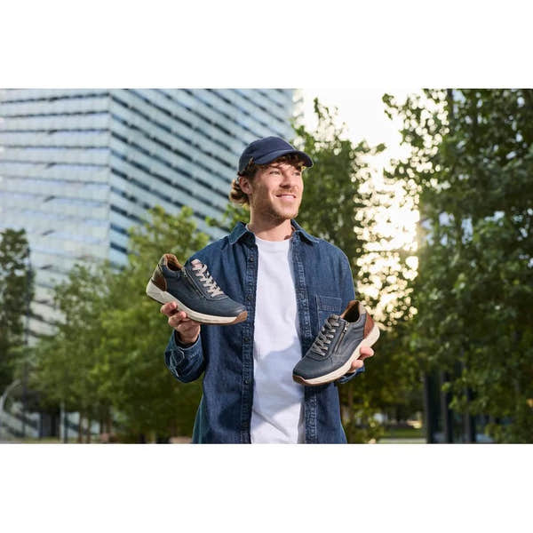 Man holding Rieker 11504-14 men's wide midnight zip and lace shoes outdoors, styled with denim shirt and cap.