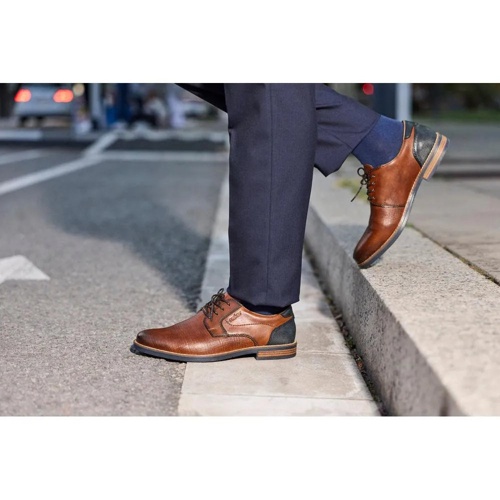 Rieker 13504-24 men's brown leather lace-up shoes, stylish ankle boots with black accents and stacked heel, on a city sidewalk.