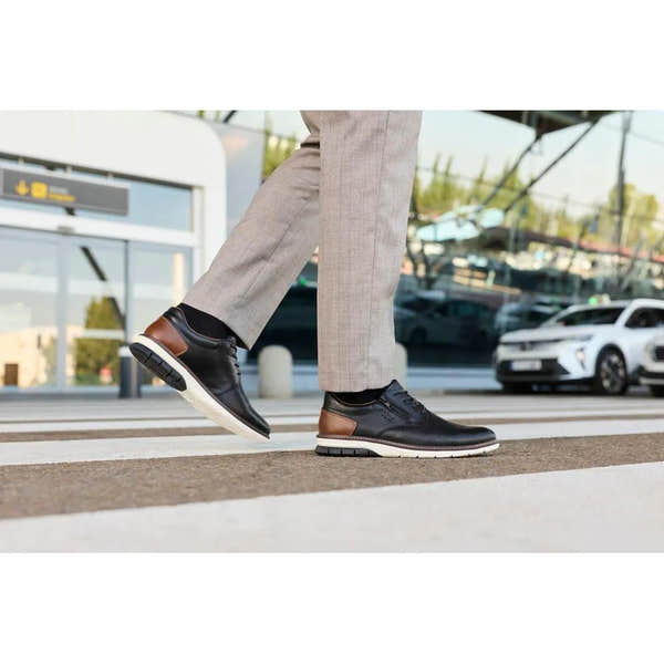 Rieker 14412-00 men's black leather zip and lace shoes with brown accents and white soles, worn with beige trousers.