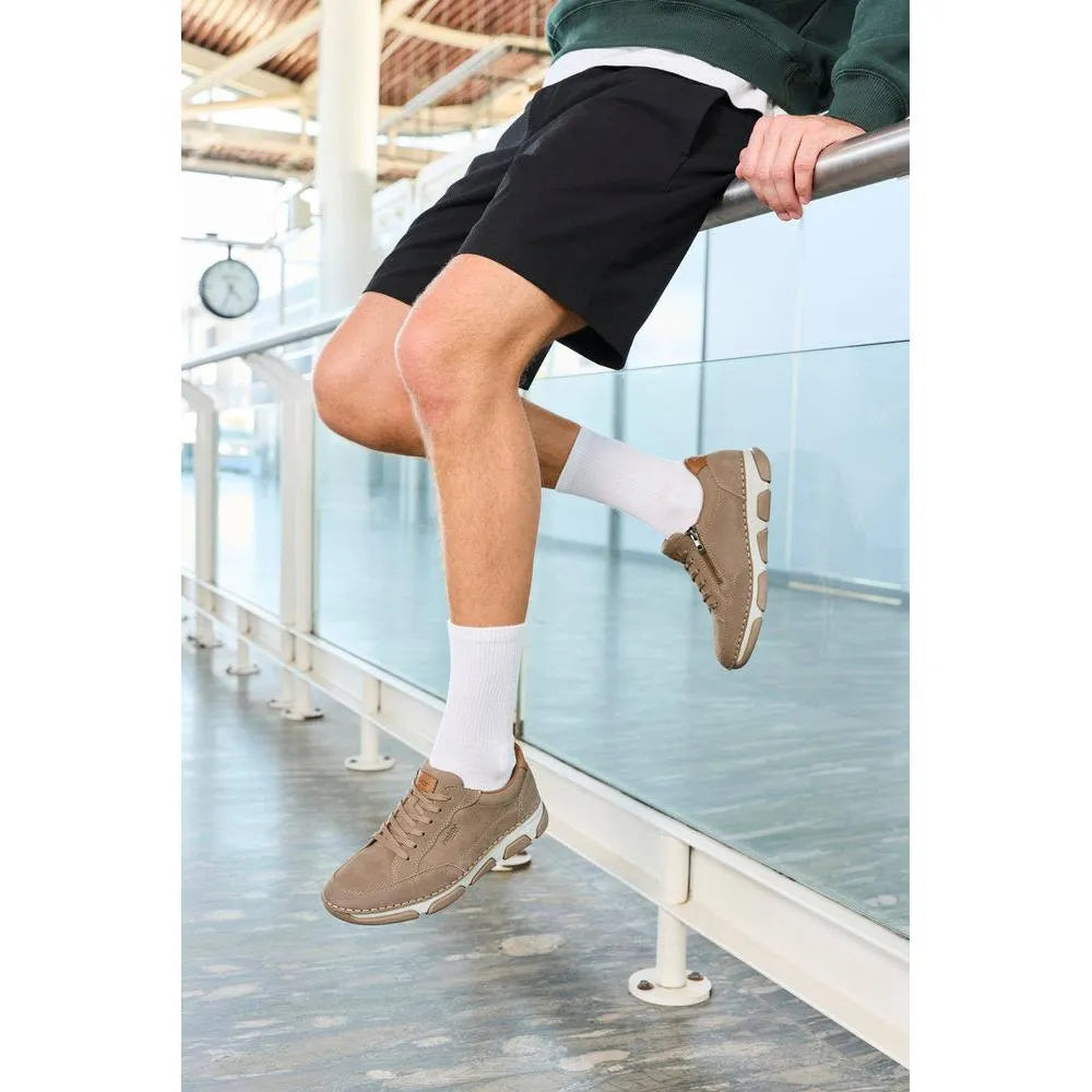Men's wide brown leather lace-up shoes with a sporty sole, paired with white socks and black shorts.