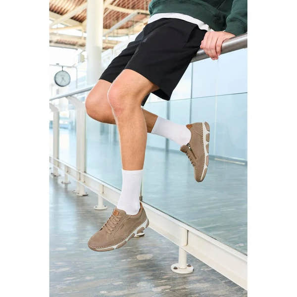 Men's wide brown leather lace-up shoes with a sporty sole, paired with white socks and black shorts.