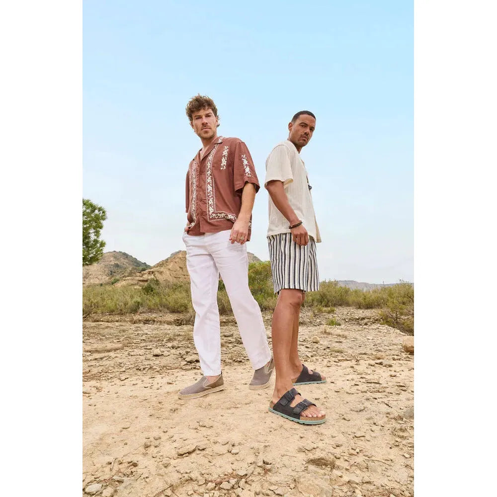 Rieker 21190-45 men's wide fit grey suede buckle mules, casual footwear in outdoor desert setting.