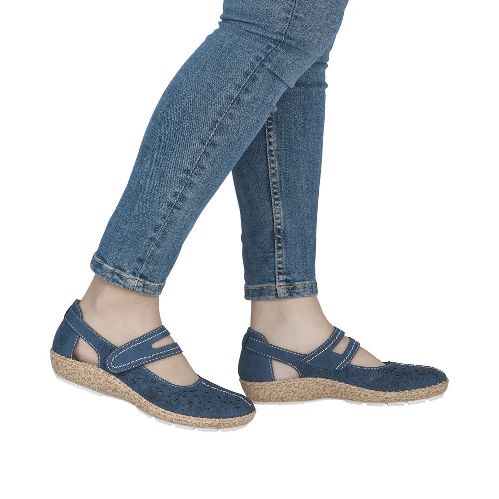 Navy touch fastening shoes with cutout floral pattern, cork-like soles, worn with blue jeans.