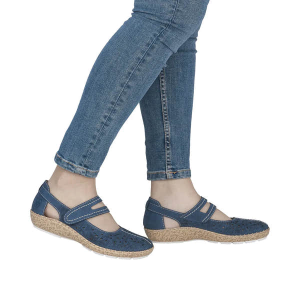Navy touch fastening shoes with cutout floral pattern, cork-like soles, worn with blue jeans.