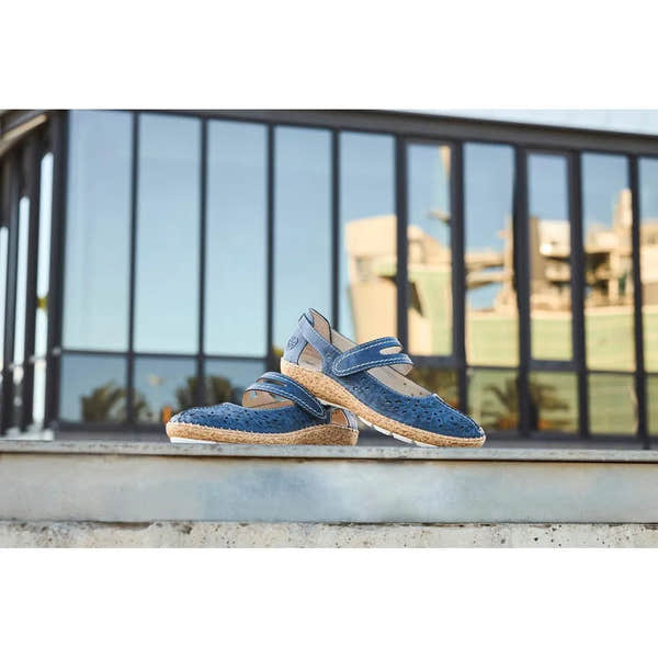 Navy blue touch fastening shoes with perforated design, jute sole, and open sides, placed outdoors near a glass railing.