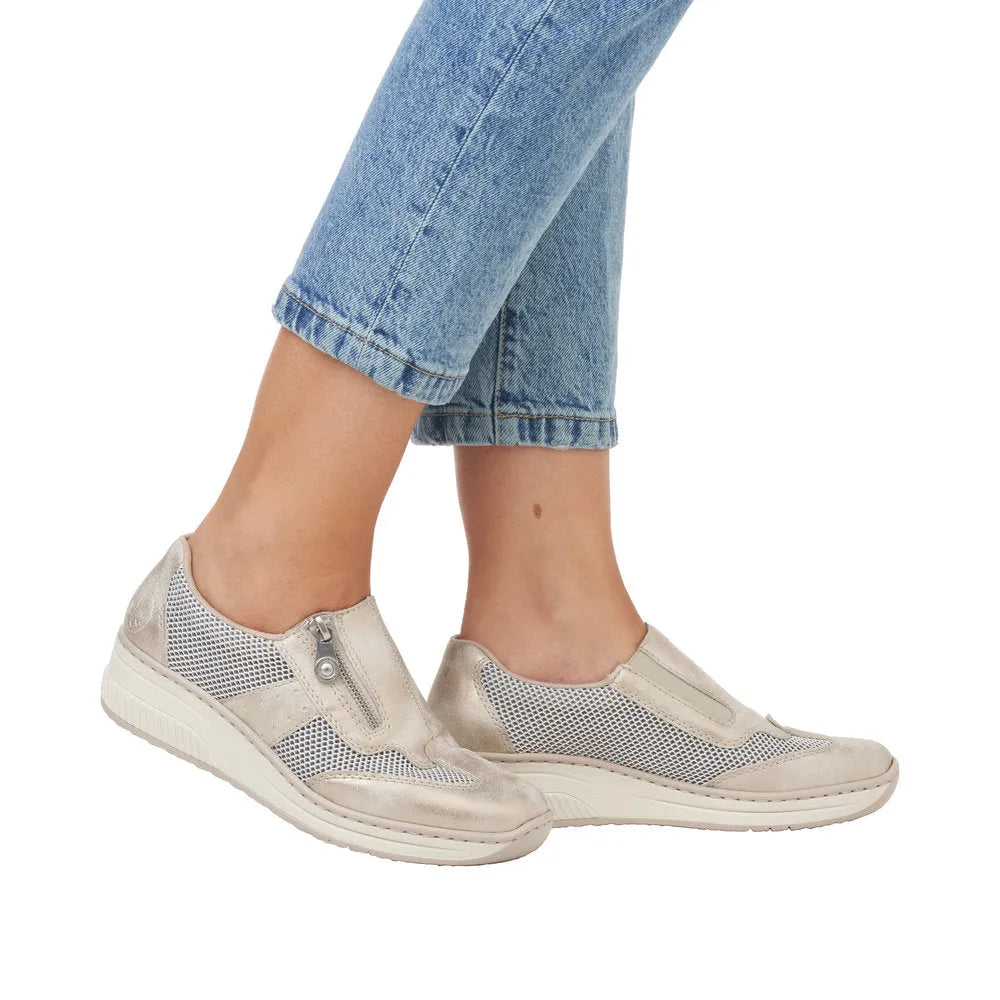 Taupe metallic slip-on shoes with mesh panels and side zip, paired with rolled blue jeans. Casual and stylish design.