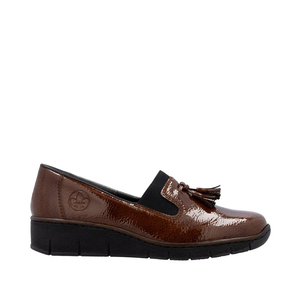 Rieker 53751-24 women's brown slip-on shoes with tassel detail, glossy finish, and black elastic side panels.