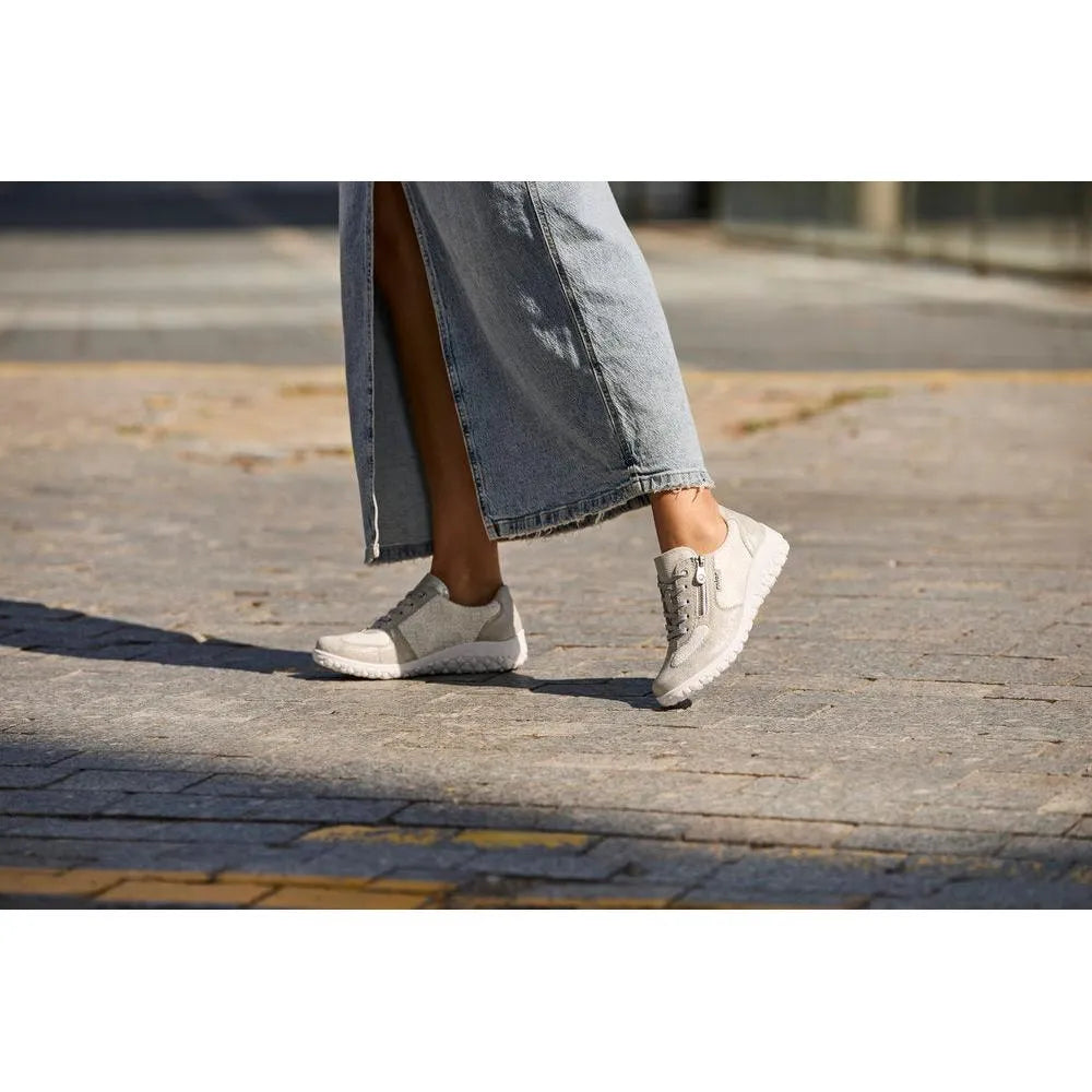 Rieker 59501-90 ladies wide white/silver zip and lace shoes worn with distressed jeans on a paved street.