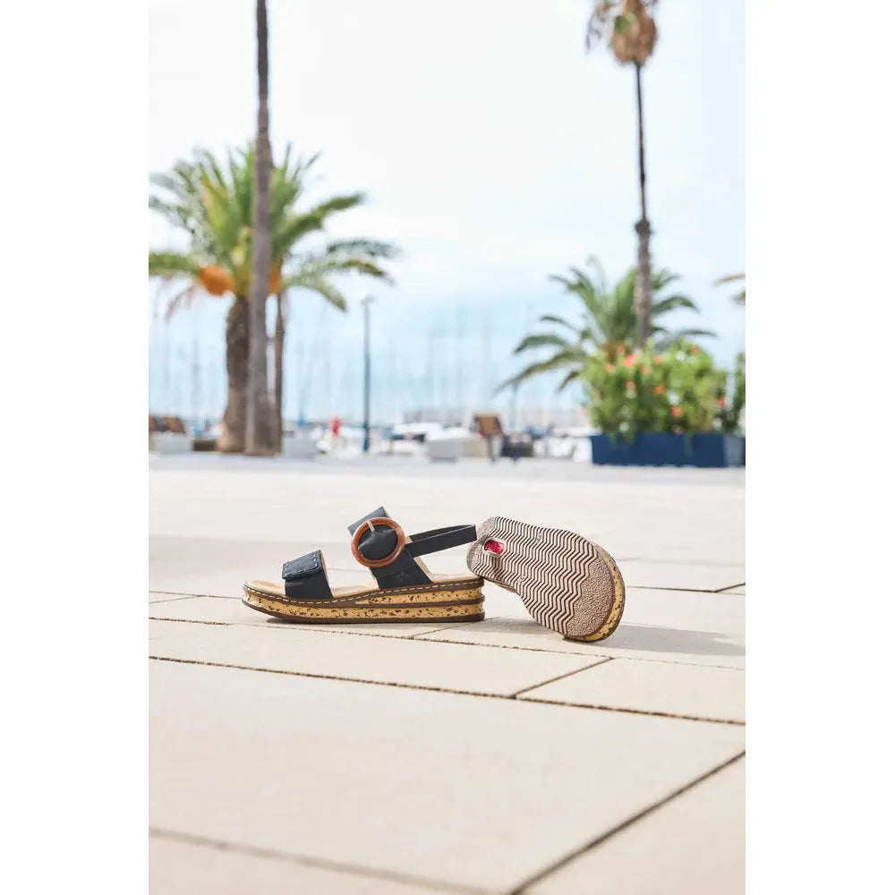 Rieker 62950-14 Ladies Pacific Blue Touch Fastening Sandals on a tiled walkway with palm trees and marina in background.