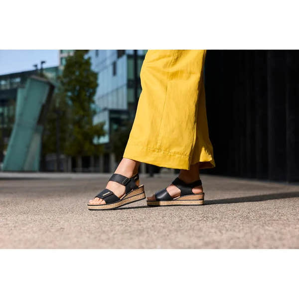 Rieker 63781-00 women's black touch fastening sandals with cork wedge sole, open toe, and adjustable straps, outdoor urban setting.