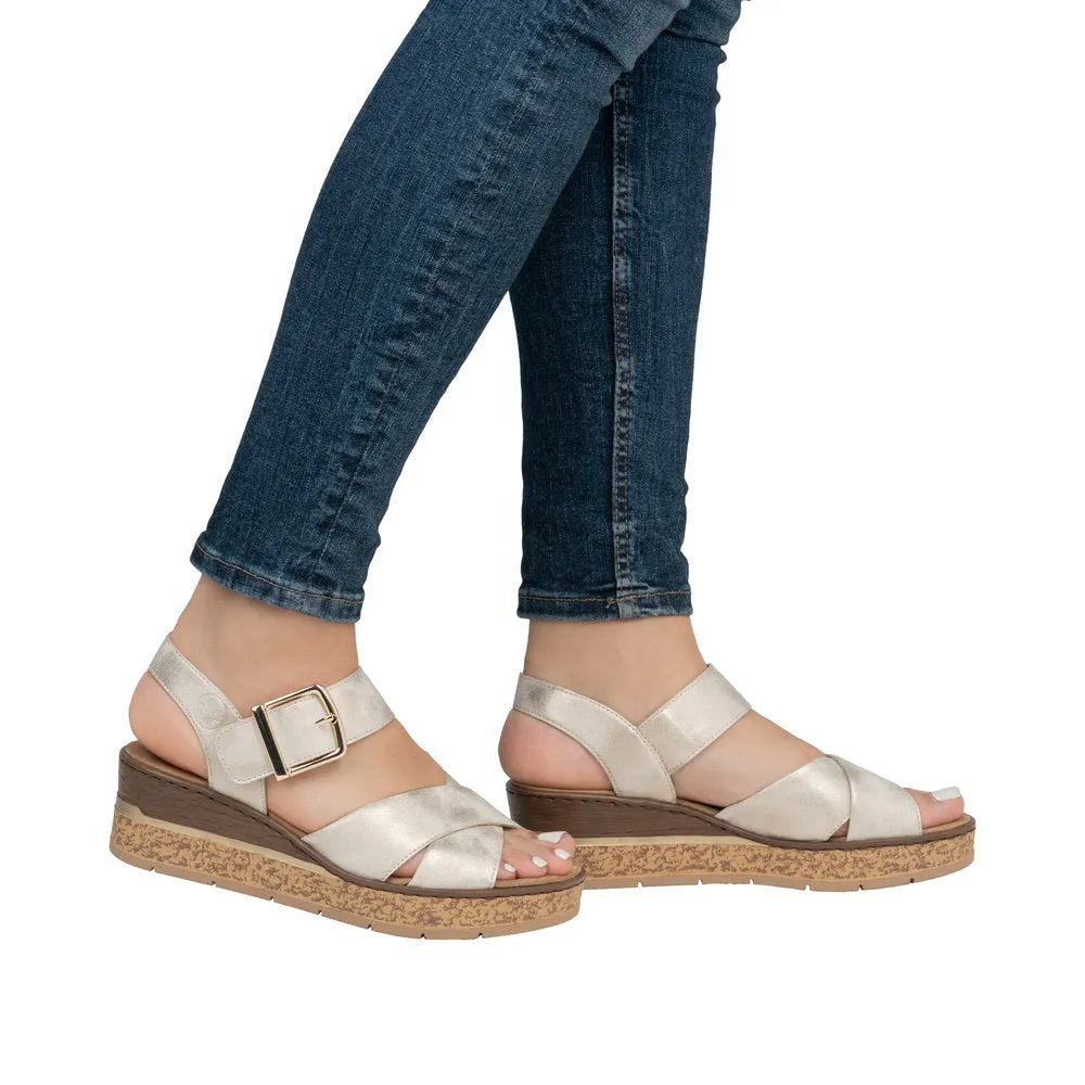 Rieker 63795-60 women's muschel buckle sandals with cream satin straps and cork wedge sole, paired with blue jeans.