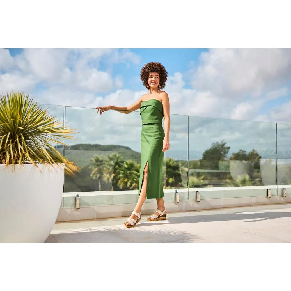 Rieker 63795-60 ladies muschel buckle sandals on a woman in a green dress, outdoor terrace with potted plant and scenic background.